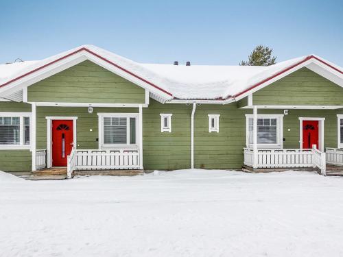 SaarenkyläにあるHoliday Home Huoneisto b2 by Interhomeの雪中の赤い扉のある緑の家