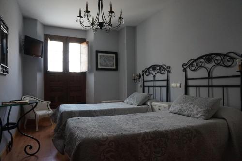 a bedroom with two beds and a chandelier at Arganzón Plaza in La Puebla de Arganzón
