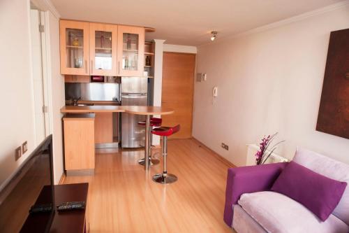 a living room with a purple couch and a kitchen at Chilean Suites Providencia in Santiago