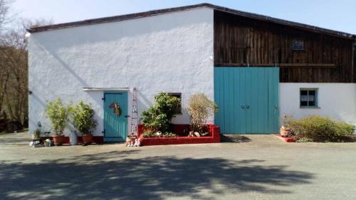 a large white building with blue doors and plants at Reitstation Roßmühle in Gräfendorf