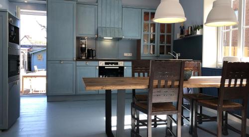 uma cozinha com armários azuis e uma mesa e cadeiras de madeira em Haus Noge Sylt - Offizierhaus Design Appartments strandnah em Westerland