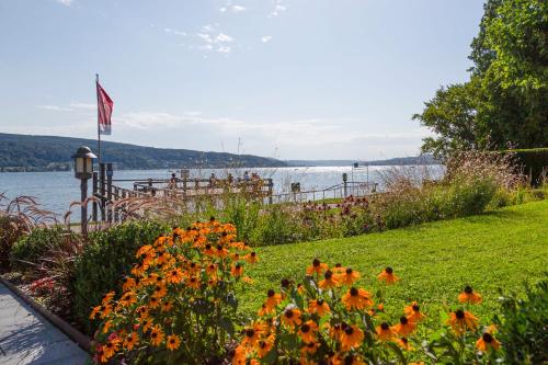 a garden with orange flowers next to a body of water at Strandhotel Löchnerhaus in Reichenau
