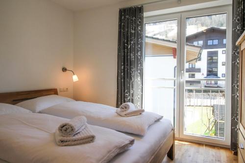 two beds in a room with a large window at Tauern Relax Lodges by we rent, SUMMERCARD INCLUDED in Kaprun