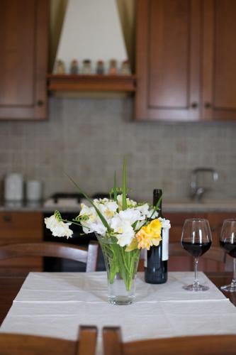 a vase of flowers on a table with wine glasses at Terremesu a Castiadas Villasimius Costa Rei in Castiadas