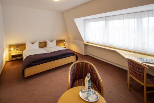 a hotel room with a bed and a table and chairs at Hotel Gloria Superior in Stuttgart