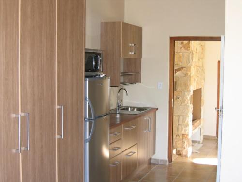 eine Küche mit einem Kühlschrank aus Edelstahl und Holzschränken in der Unterkunft Oubaai Ocean View Private Self catering rooms Herolds Bay in George