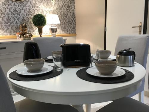 une table blanche avec des bols et des tasses dessus dans l'établissement Appartement Médicis avec Garage, à Honfleur