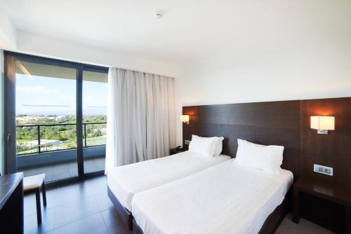 a hotel room with two beds and a large window at RR Alvor Baía Resort in Alvor
