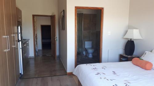 a bedroom with a white bed and a bathroom at Oubaai Ocean View Private Self catering rooms Herolds Bay in George