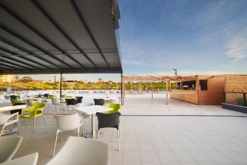 a patio with tables and chairs and a building at RR Alvor Baía Resort in Alvor
