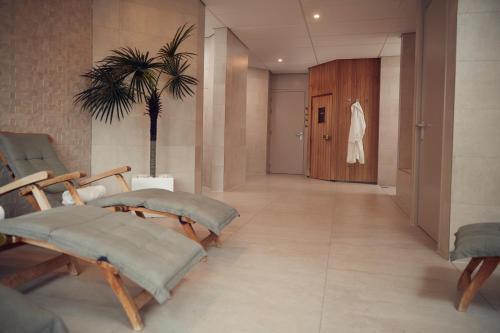 un couloir avec des chaises, une porte et un palmier dans l'établissement WestCord Hotel Schylge, à West-Terschelling