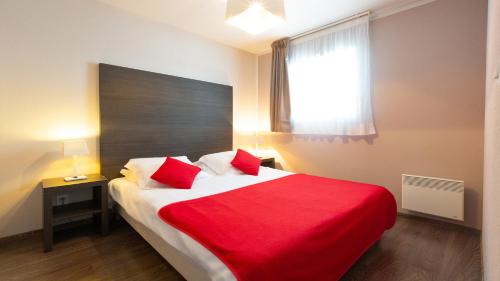 - une chambre dotée d'un grand lit avec des draps rouges et d'une fenêtre dans l'établissement Vacancéole - Le Domaine du Mont - Mont St Michel, à Roz-sur-Couesnon
