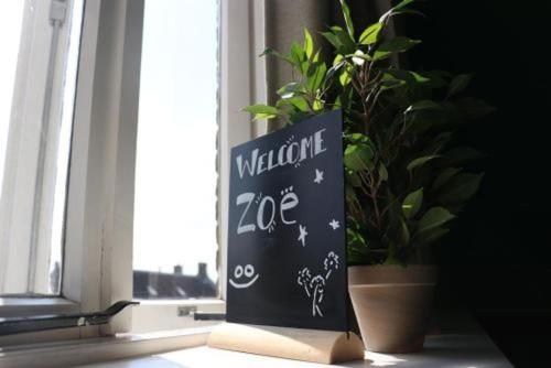 a sign sitting in a window next to a potted plant at Hostel Roots in Tilburg