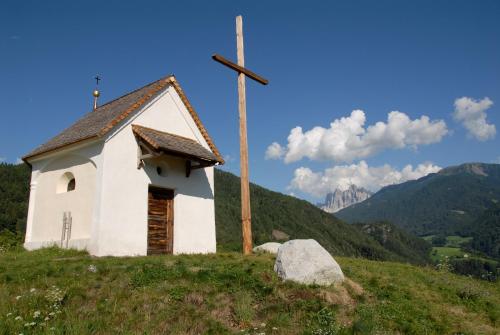 a small chapel with a cross on top of a hill at Gasthof Teiser Stern in Funes