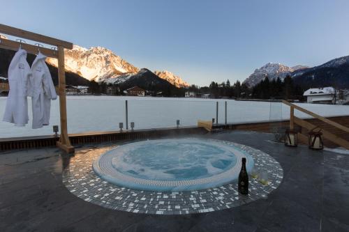 einem Whirlpool auf einem Deck neben einem Wasserkörper in der Unterkunft Mountainlodge Luxalpine in St. Vigil