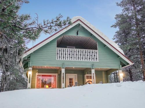 Holiday Home Jäkälätieva by Interhome في Raattama: بيت اخضر في الثلج اشجار
