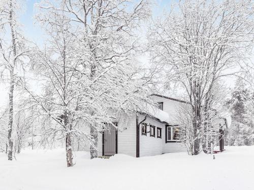 a house covered in snow in front of trees at Holiday Home Tieva by Interhome in Peltovuoma