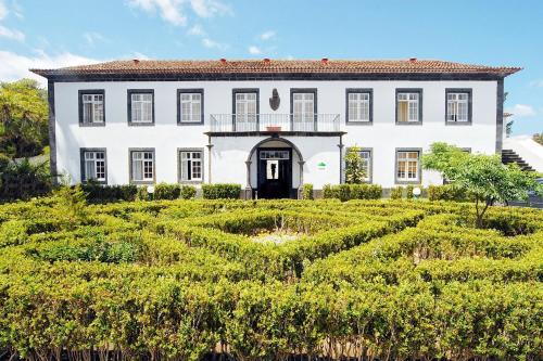 Azores Youth Hostels - Sao Miguel في بونتا ديلغادا: بيت ابيض كبير وامامه حديقه