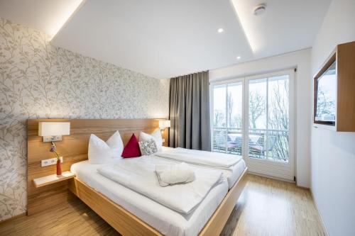 a bedroom with a large bed and a large window at Appartementhotel Röhrenbach in Immenstaad am Bodensee