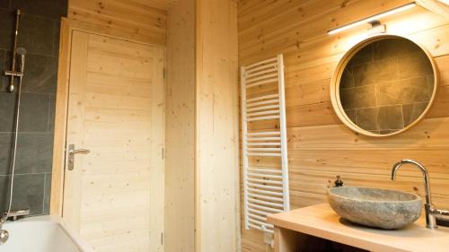 a bathroom with a wooden wall with a sink and a mirror at Le Chalet de Juliette in Besse-et-Saint-Anastaise