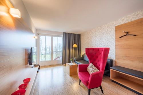 ein Wohnzimmer mit einem roten Stuhl und einem Sofa in der Unterkunft Appartementhotel Röhrenbach in Immenstaad am Bodensee