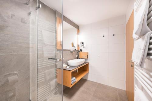 a bathroom with a sink and a glass shower at Appartementhotel Röhrenbach in Immenstaad am Bodensee