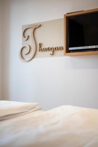 a sign on a bed with a television on a wall at Appartementhotel Röhrenbach in Immenstaad am Bodensee