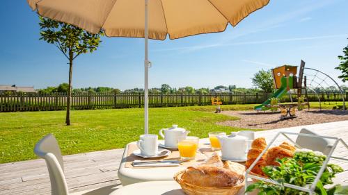 ein Tisch mit Brot, Orangensaft und einem Regenschirm in der Unterkunft Vacancéole - Le Domaine du Mont - Mont St Michel in Roz-sur-Couesnon
