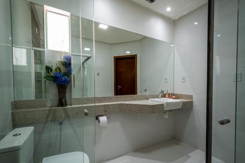 a bathroom with a toilet and a sink and a mirror at W4 Hotel in Irecê