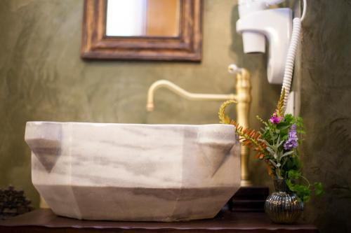 a bathroom with a stone sink and a vase with flowers at Porolithos Boutique Hotel in Rhodes Town