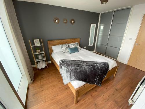 a bedroom with a large bed with a wooden floor at Tailor That Property - Chelsea House in Milton Keynes