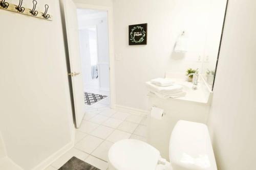 a white bathroom with a toilet and a sink at Dwell Proper 2 Bedroom Condo in Martinez
