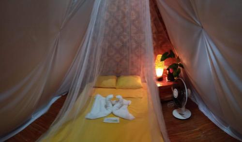 a room with a bed with a curtain and shoes at SHUKRAN Apartelle in Siquijor
