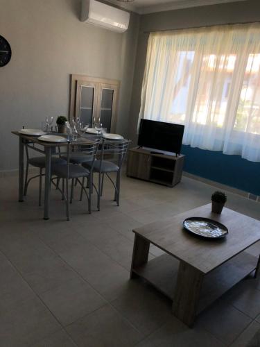 comedor con mesa, sillas y TV en Central Apartment en Agios Nikolaos