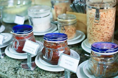 a group of jars of food on plates with labels at Pousada da Ladeira in Pipa