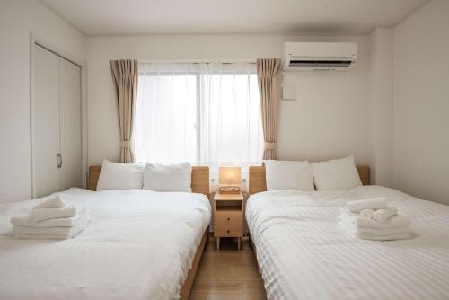 2 Betten in einem kleinen Zimmer mit Fenster in der Unterkunft Noah Ikebukuro / Vacation STAY 7325 in Tokio