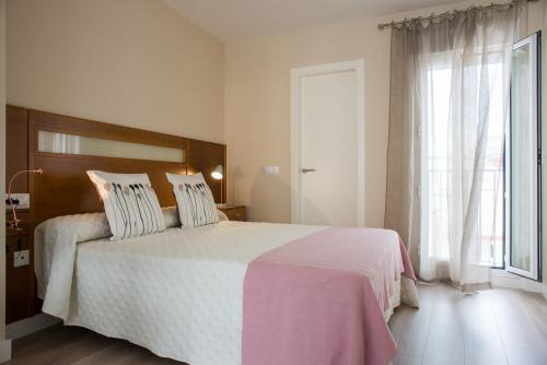 Un dormitorio con una cama grande y una ventana. en La Posada del Mercado, en Cádiz