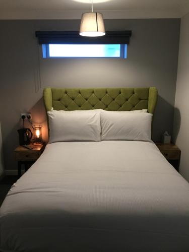 a bedroom with a bed with a green headboard and a window at The Reubens in Bedale