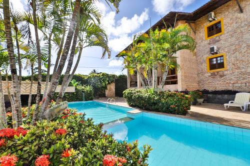 a swimming pool in front of a house with palm trees at Pousada da Ladeira in Pipa