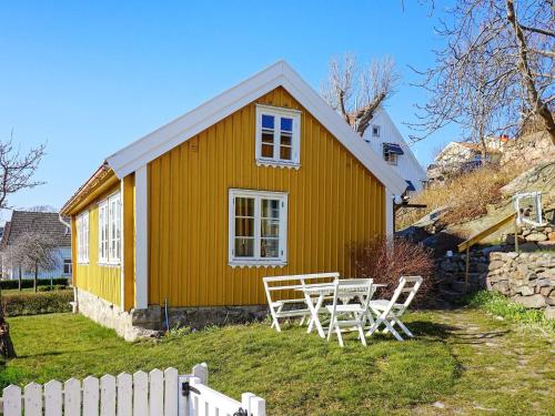 a yellow house with a table and chairs in the yard at 5 person holiday home in GREBBESTAD in Grebbestad