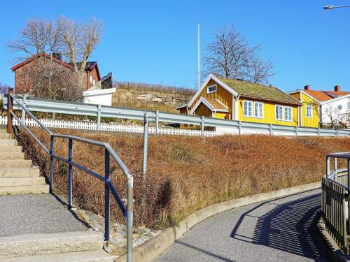 una casa amarilla en una colina con una valla y escaleras en 5 person holiday home in GREBBESTAD en Grebbestad