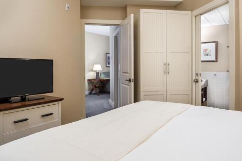 a bedroom with a white bed and a flat screen tv at Summerland Waterfront Resort & Spa in Summerland