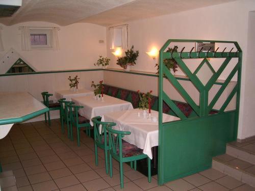 un restaurante con mesas blancas y sillas verdes en Apart Hotel Taucha en Taucha