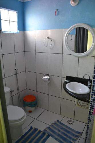 a bathroom with a toilet and a sink and a mirror at Itaoca Pousada Camping in Itaipava