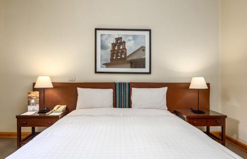 een slaapkamer met een bed met 2 nachtkastjes en 2 lampen bij LP Los Portales Hotel Tarma in Tarma