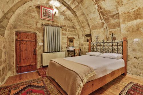 Un dormitorio con una cama grande en una pared de piedra. en Kookaburra Hotel, en Göreme