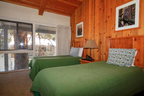 1 dormitorio con 2 camas verdes y ventana en Sierra Park Villas #23, en Mammoth Lakes