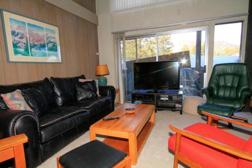 a living room with a black leather couch and a tv at Sierra Park Villas #24 in Mammoth Lakes