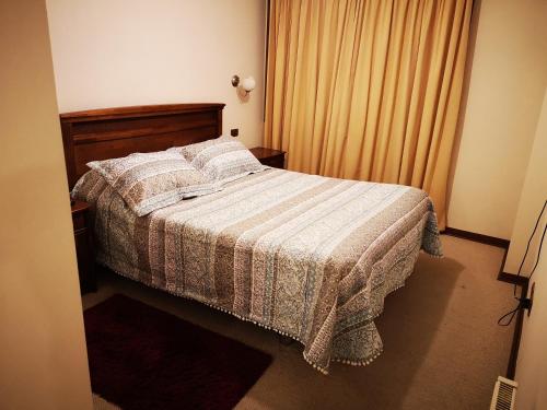 a bedroom with a bed with a striped blanket at Departamento Central Ohiggins in Concepción