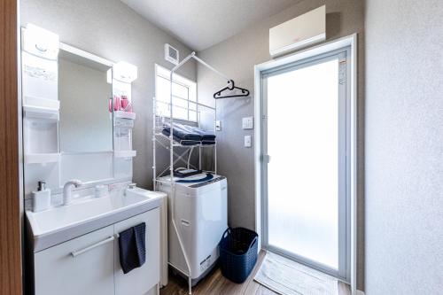 uma casa de banho branca com um lavatório e um espelho em Bon Moment A棟-紅葉館 em Fujikawaguchiko